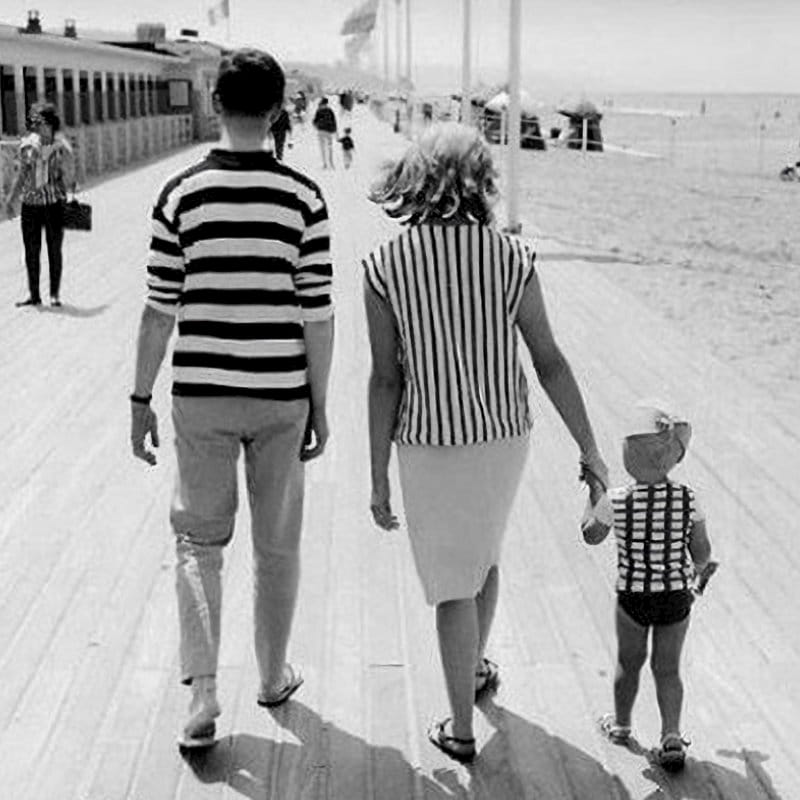 family walking along a boardwalk at the beach.